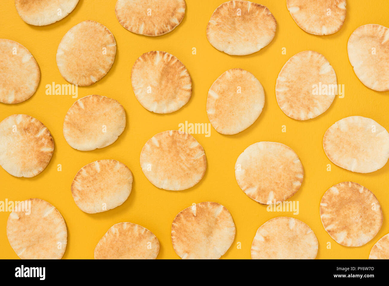 Lots of freshly baked mini pita bread on bright yellow background Stock