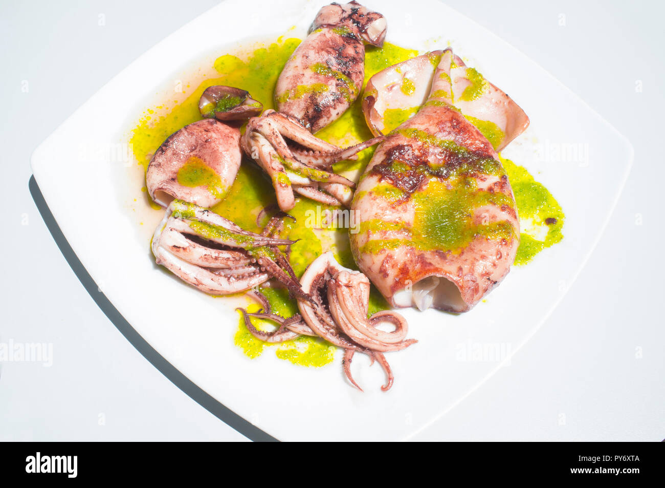 Griddle cuttlefish seasoned with green parsley sauce. Overhead shot Stock Photo