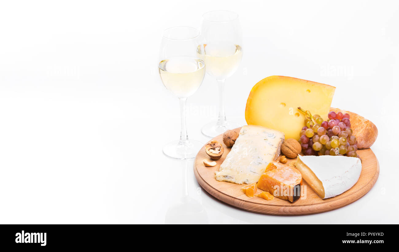 Cheese board with grapes and white wine isolated on white background. Variety of soft and hard cheeses Stock Photo