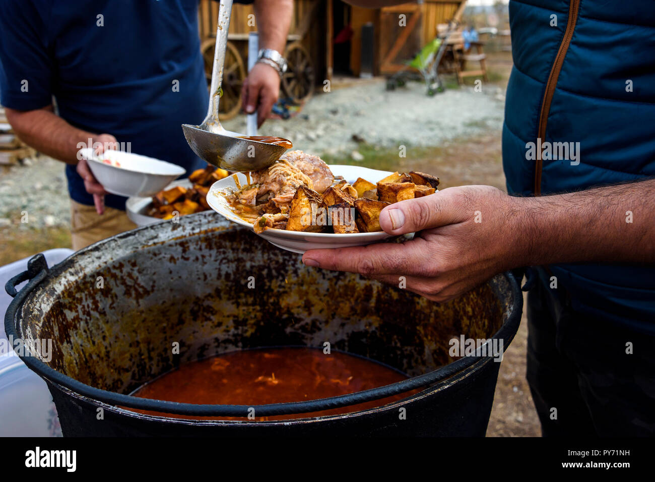 Romanian traditional food prepared in copper cauldrons. Serving rabbit stew with fried potatoes . Stock Photo