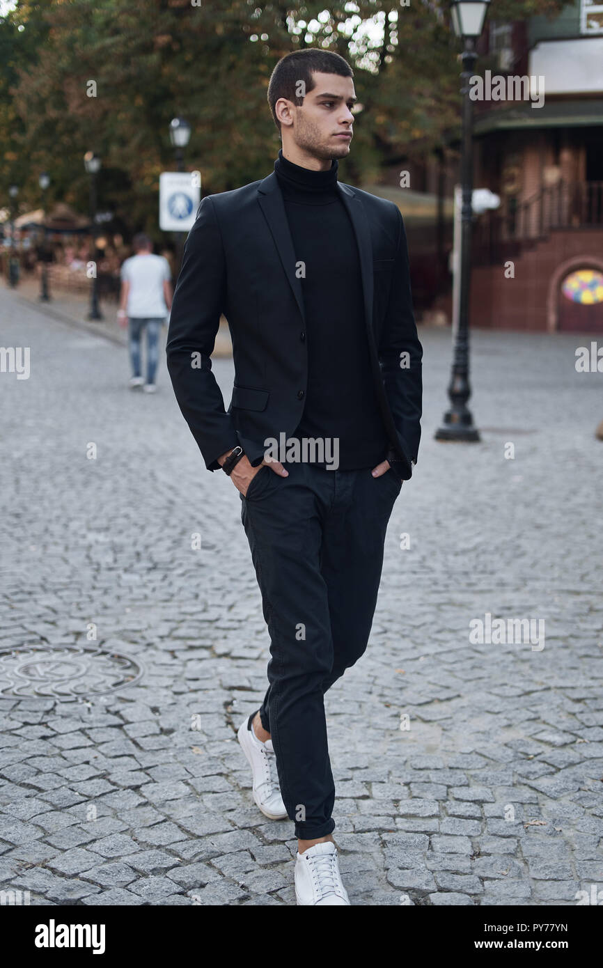Young man walking, smart casual on an autumn day on a street of European City. Lifestyle Photography Stock Photo