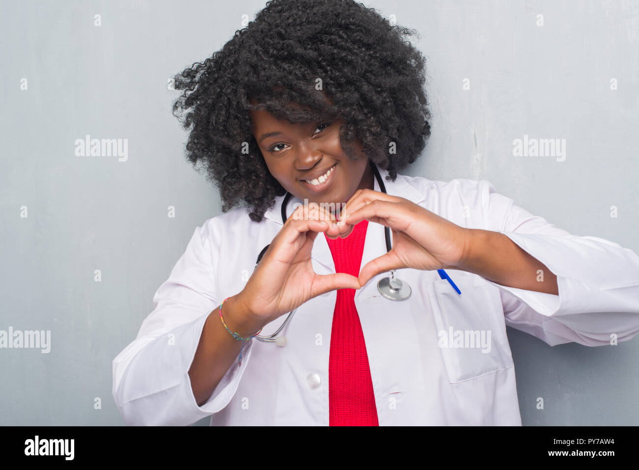 Young african american doctor woman over grey grunge wall smiling in ...