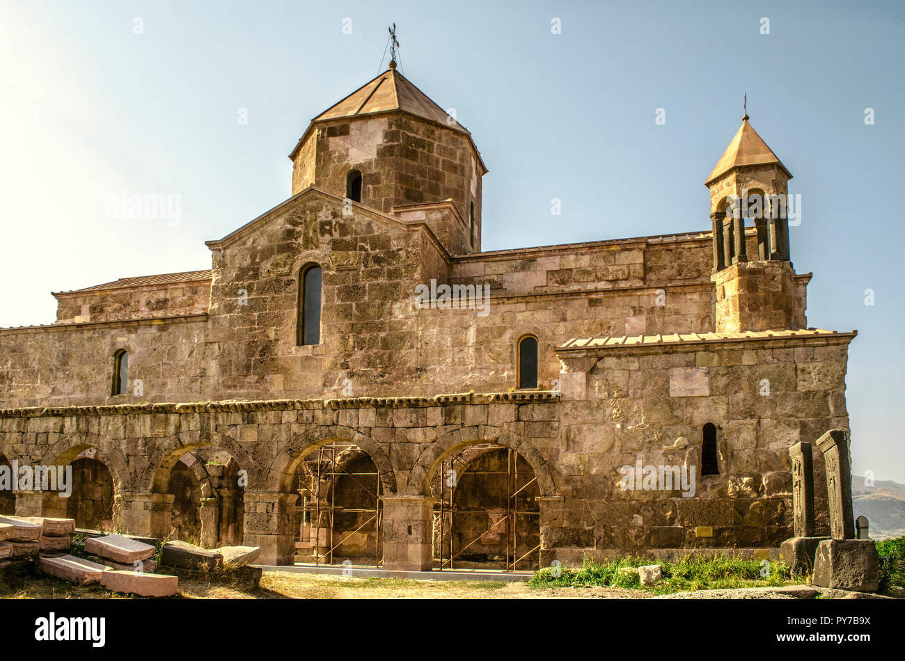 Odzun monastery with an arched gallery and bell tower, basalt crosses on the south side at sunset Stock Photo