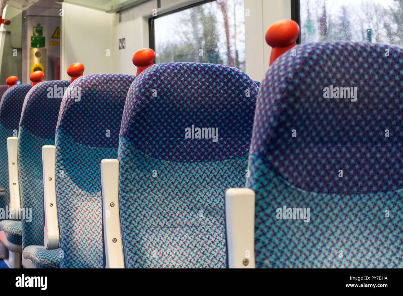 Row of empty seats on a train carriage with red grip handles. NI Railways, Translink, Belfast, N.Ireland. Stock Photo