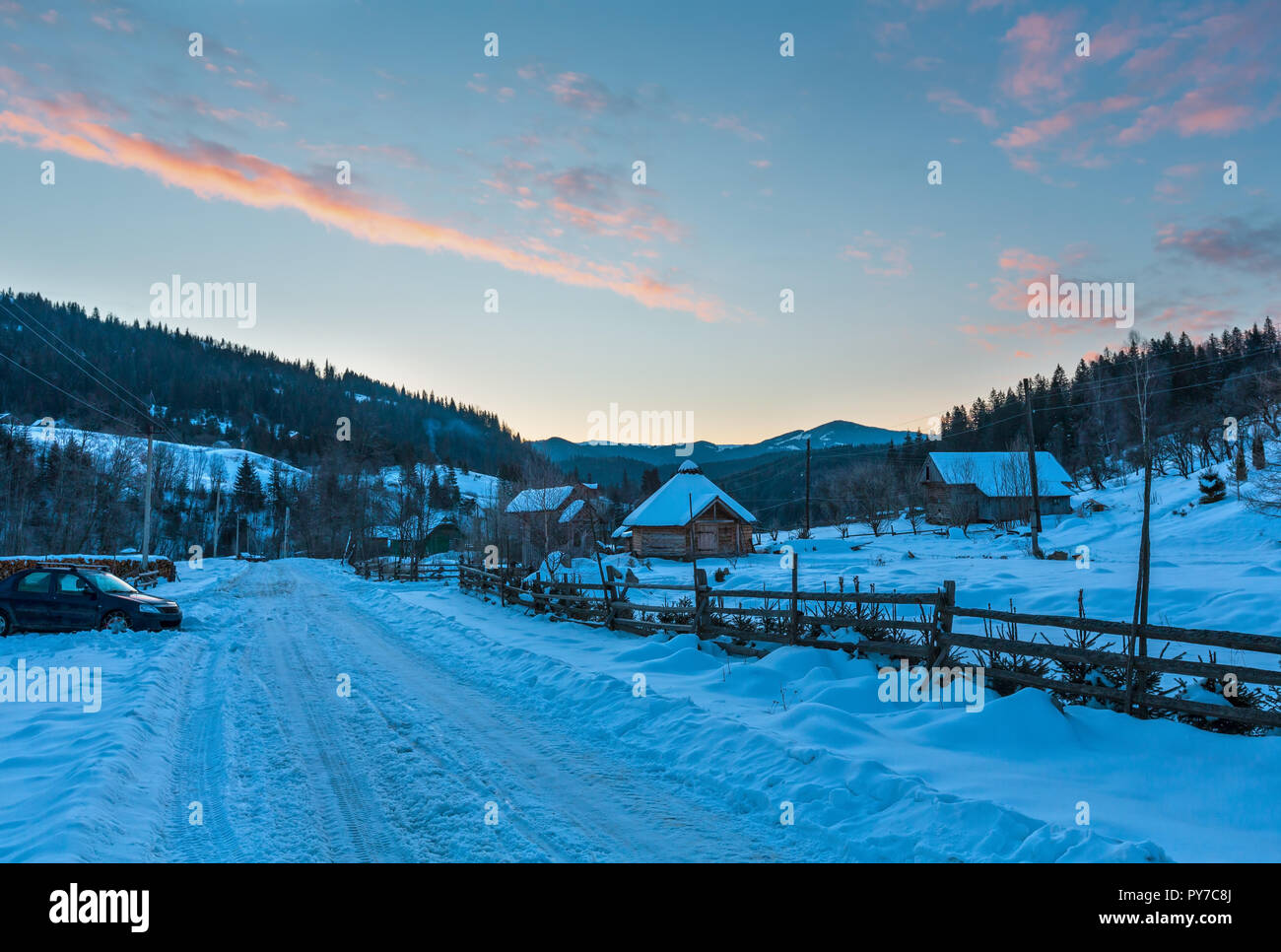 Daybreak sunrise morning winter mountain village snow covered street (Ukraine, Carpathian Mountains, tranquility peaceful Dzembronya village). Stock Photo