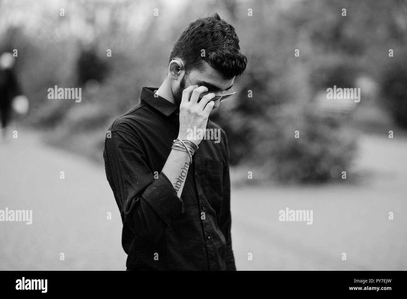Indian stylish man at black shirt and sunglasses posed outdoor. Black and white photo. Stock Photo