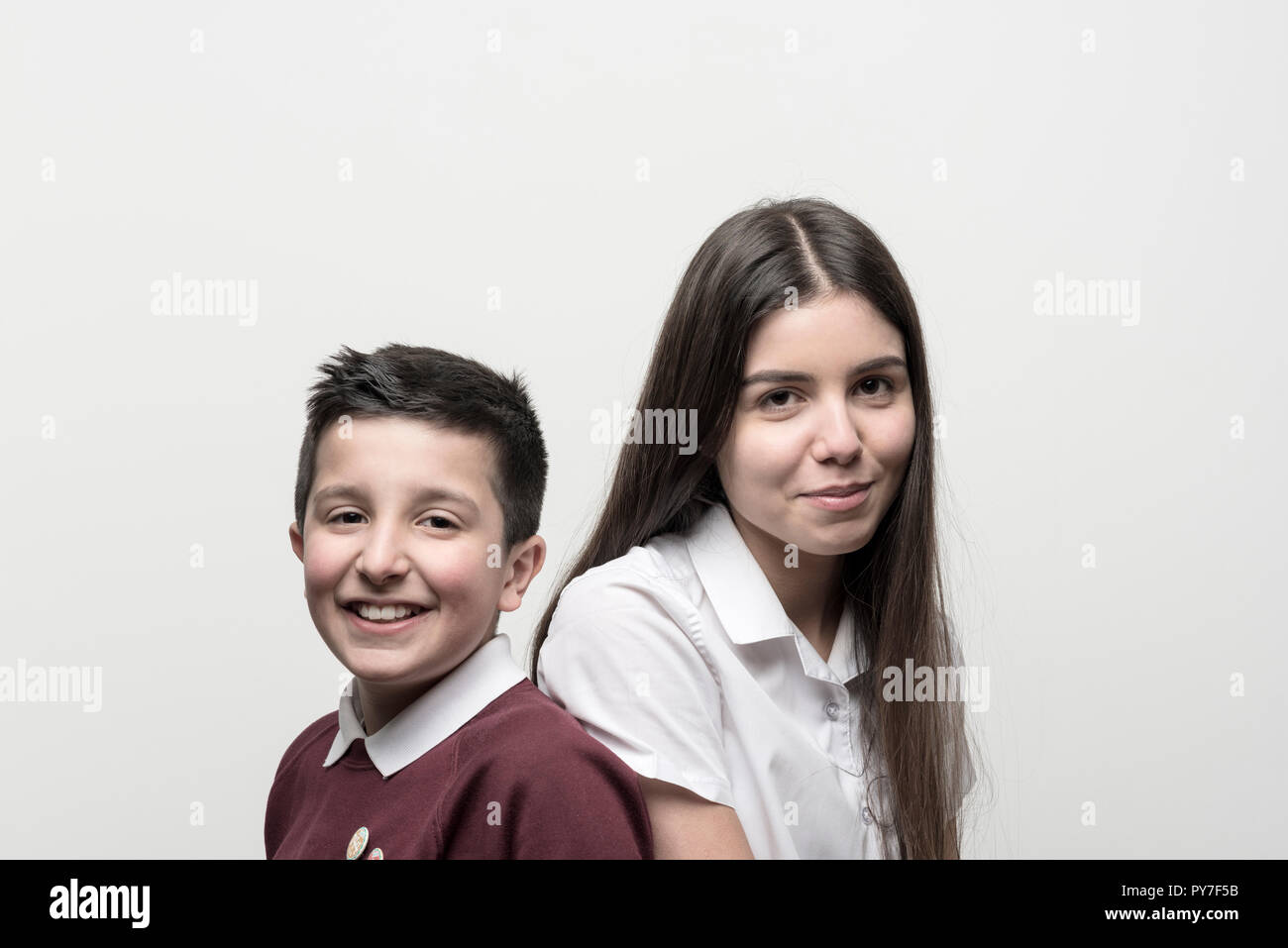 UK,England, Portrait of 10 years old boy and his teenage sister , both in school unoforms . Studio settings Stock Photo