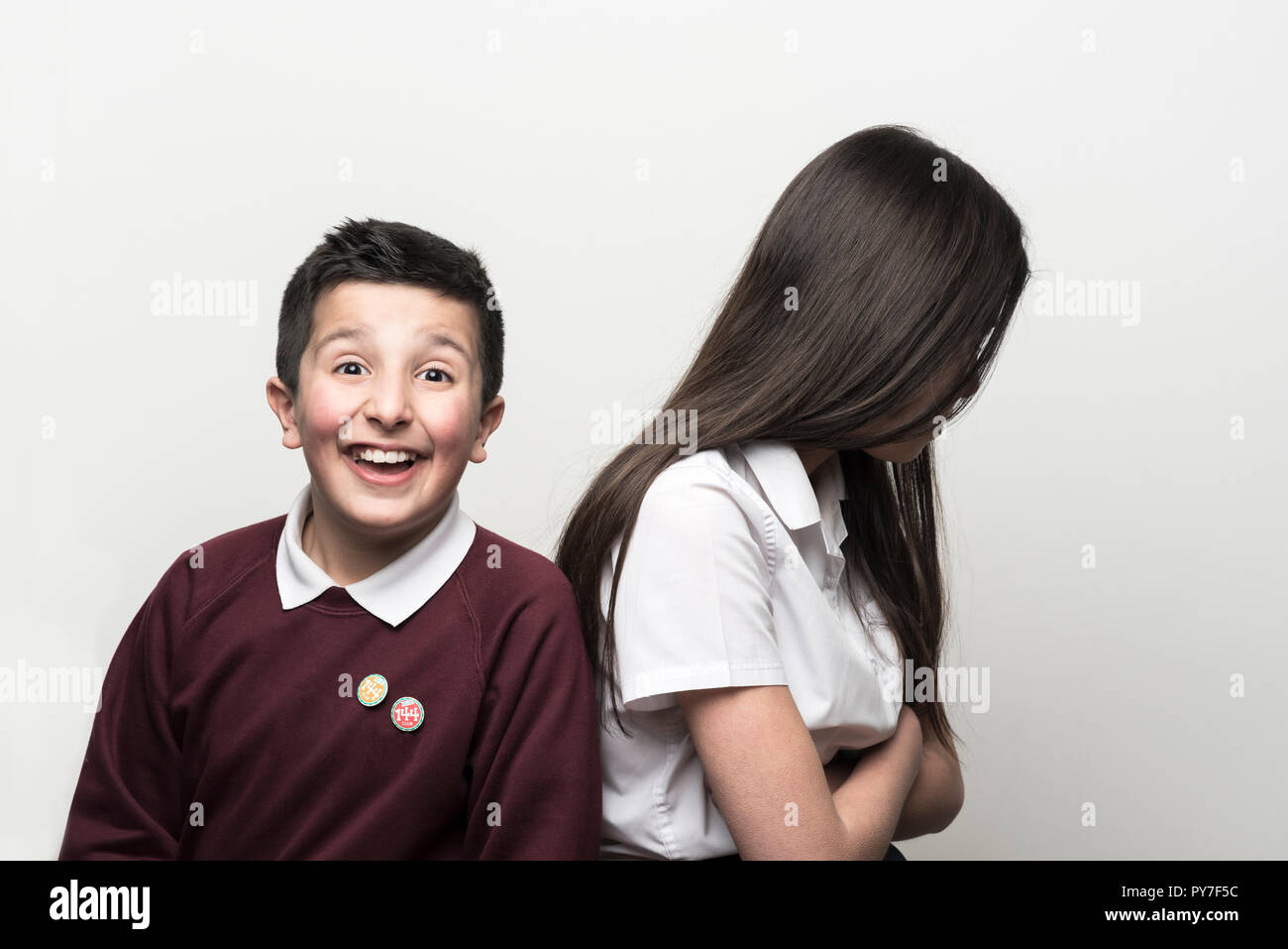 UK, Siblings, brother and older sister. 10 years old pulling funny faces next to his teenage sister.Studio settings Stock Photo