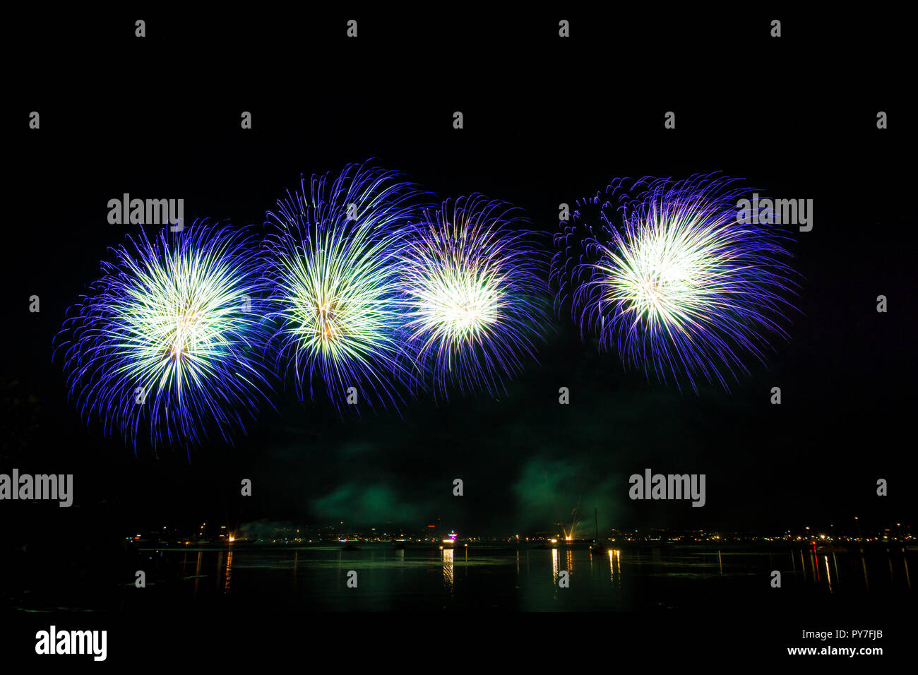 Four blue fire balls of explosions of fireworks in night water landscape Stock Photo
