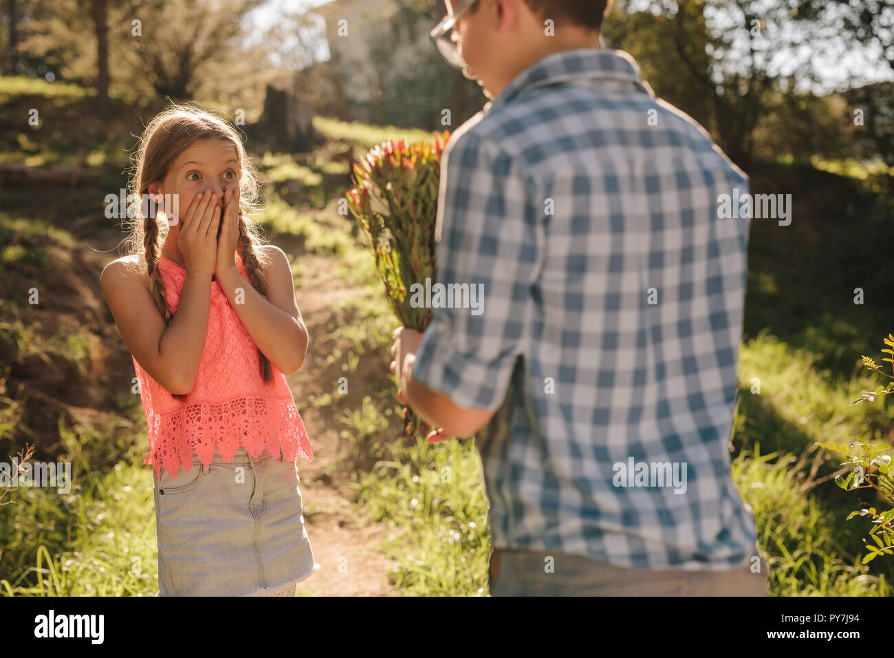 Young boy proposing to a girl with a bouquet of flowers standing ...