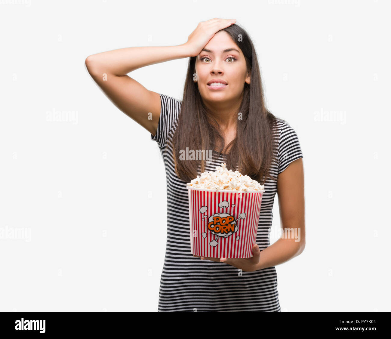 Young beautiful hispanic eating popcorn stressed with hand on head