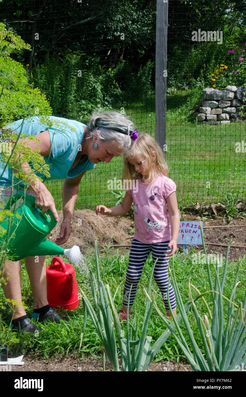 Young girl and teacher watering garden in Garden camp, Maine, USA Stock Photo