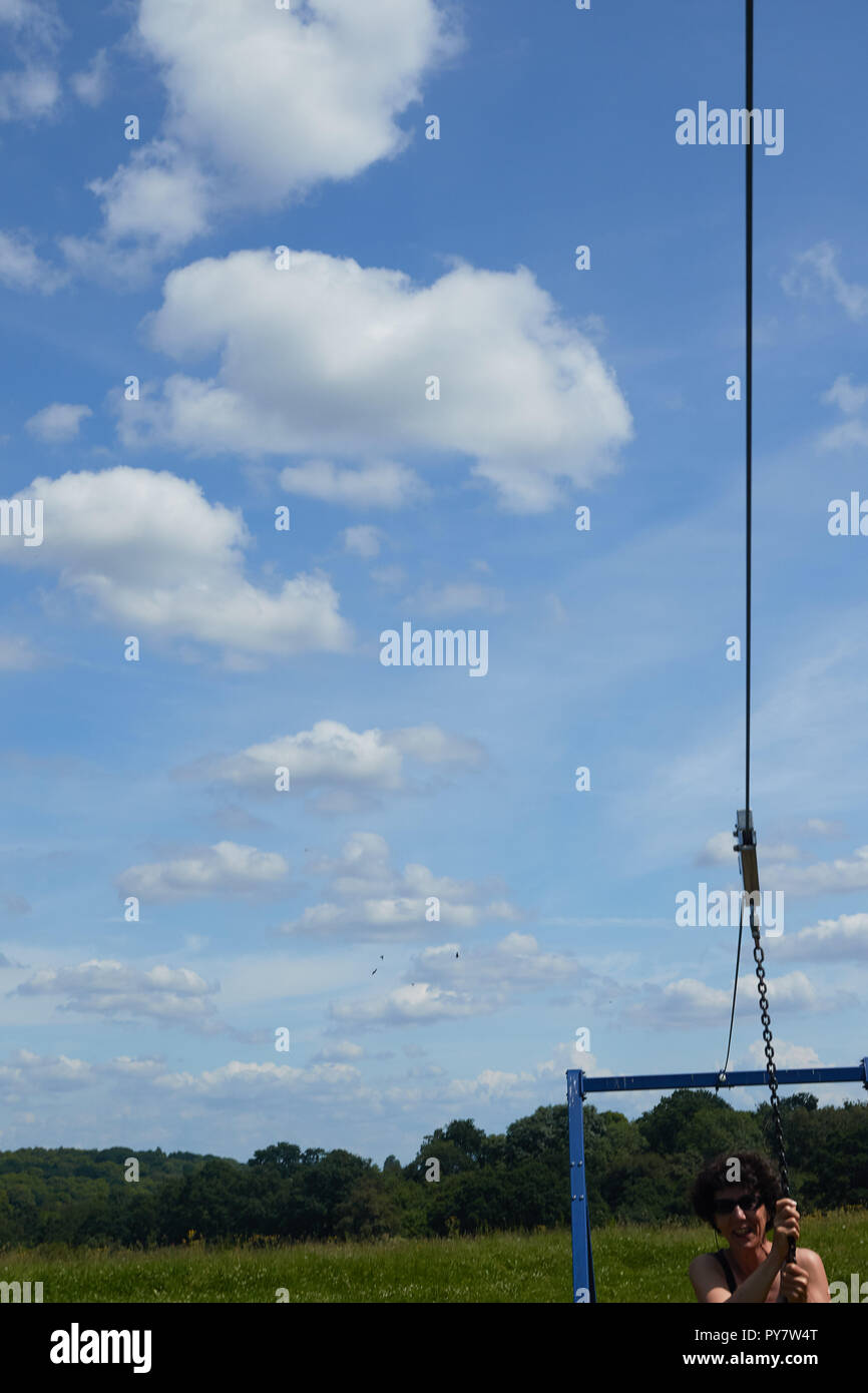 Zipline and billowing clouds in blue summer sky Stock Photo
