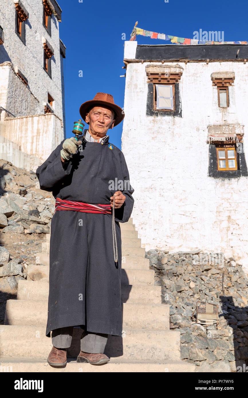 Elderly man with a prayer wheel in front of Spituk Gompa, Leh district, Ladakh, India Stock Photo