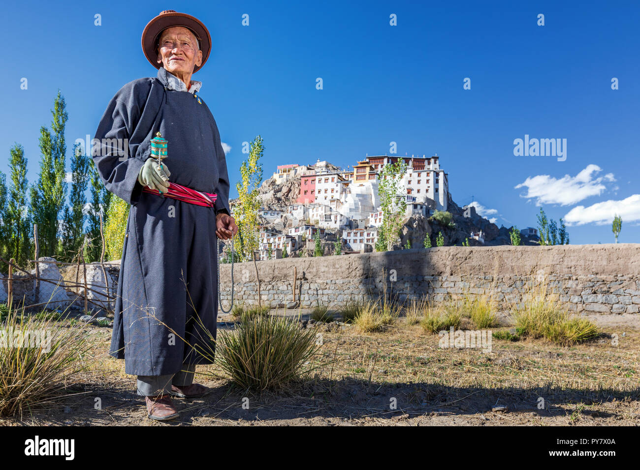 Elderly man with a prayer wheel in front of Spituk Gompa, Leh district, Ladakh, Kashmir, India Stock Photo