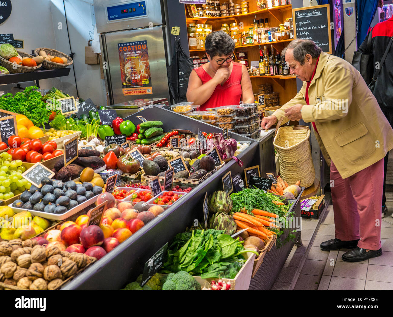 CONCARNEAU fruit & vegetable market stall with mature shopper counting & paying for produce in euros coins, Halles Market Concarneau Brittany France Stock Photo