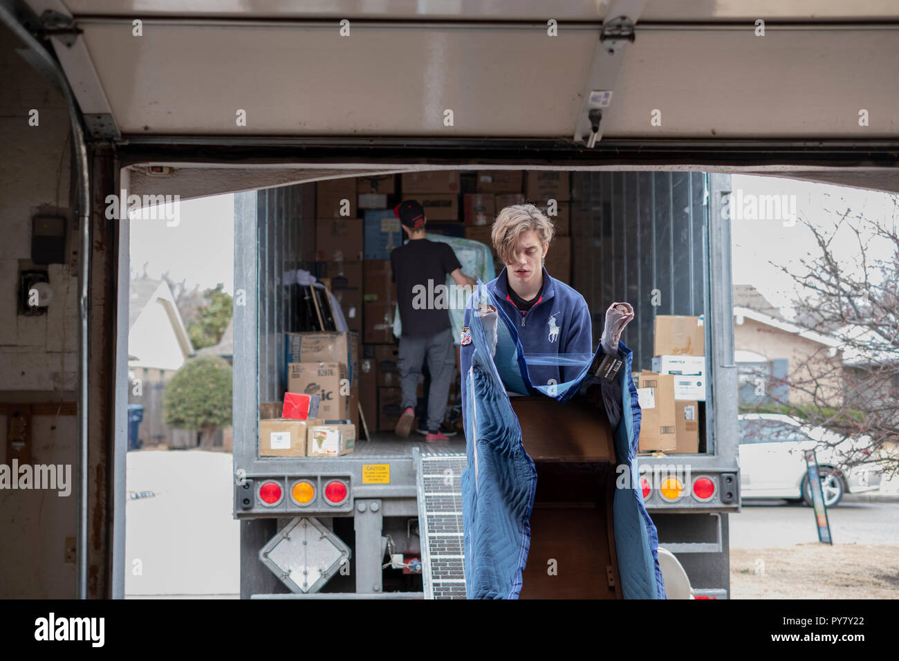 Two young Caucasian men employees of a moving company load furniture in moving van. Oklahoma City, Oklahoma, USA. Stock Photo