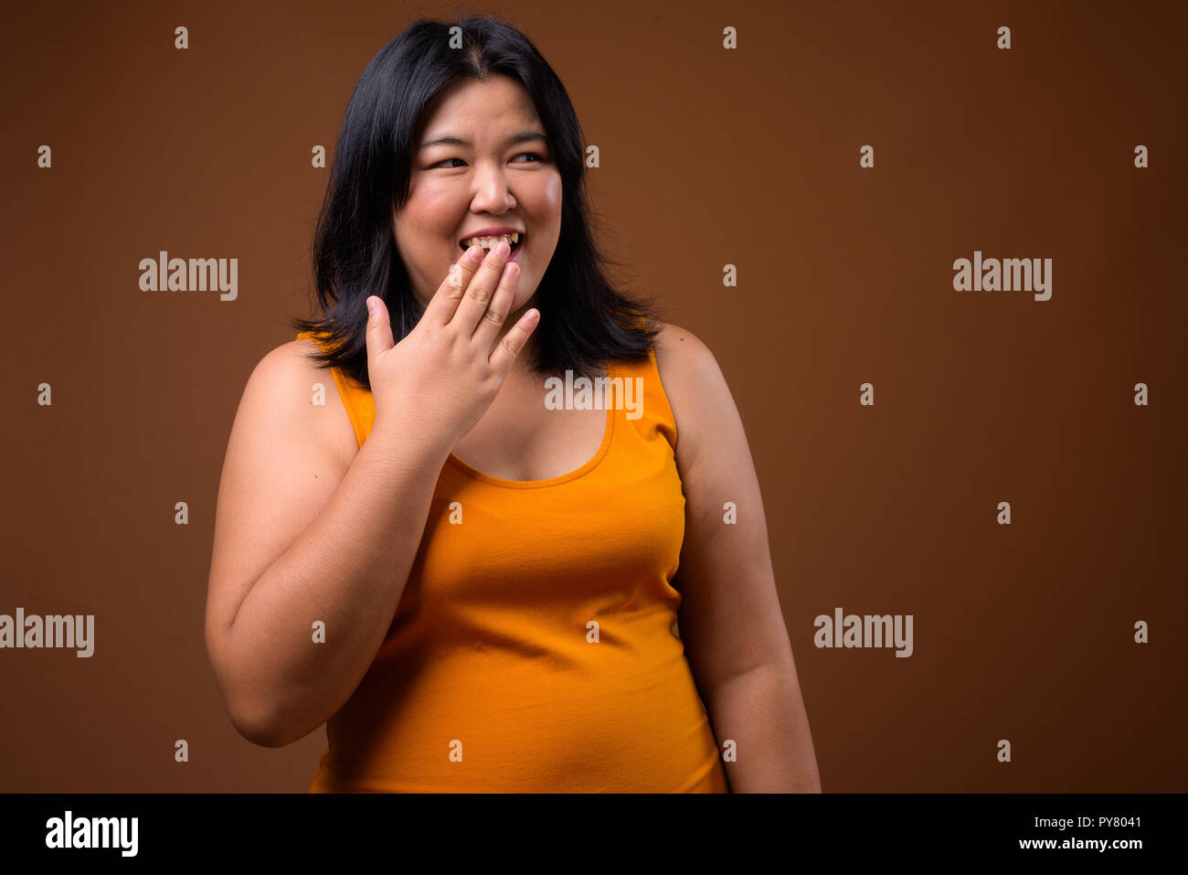 Happy overweight Asian woman laughing and covering mouth Stock Photo