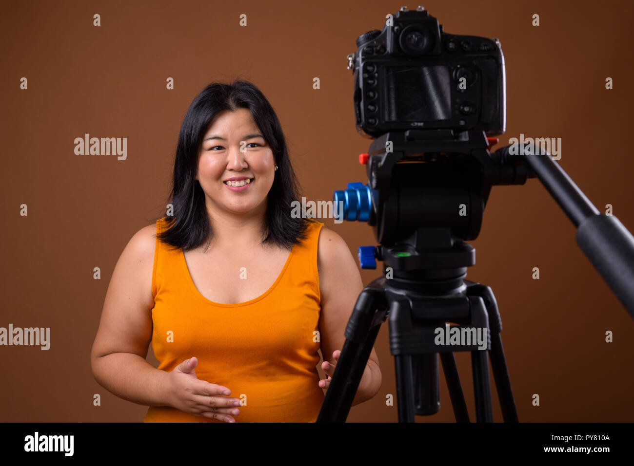 Beautiful overweight woman vlogging in studio with dslr camera on tripod Stock Photo