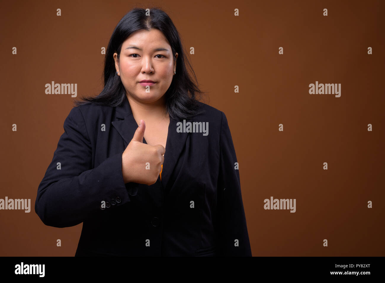 Beautiful overweight Asian businesswoman giving thumb up Stock Photo