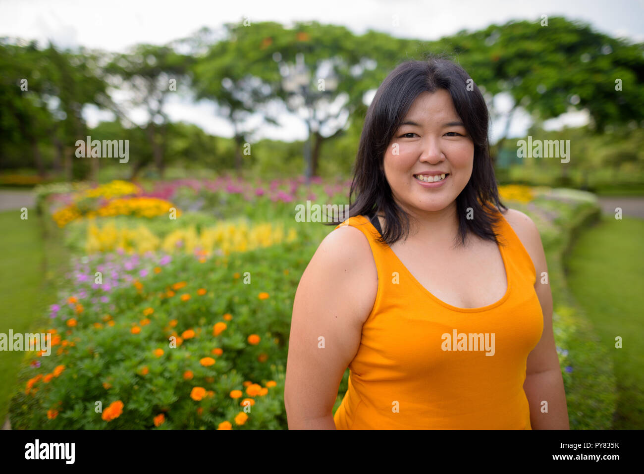 Beautiful overweight Asian woman smiling in park Stock Photo