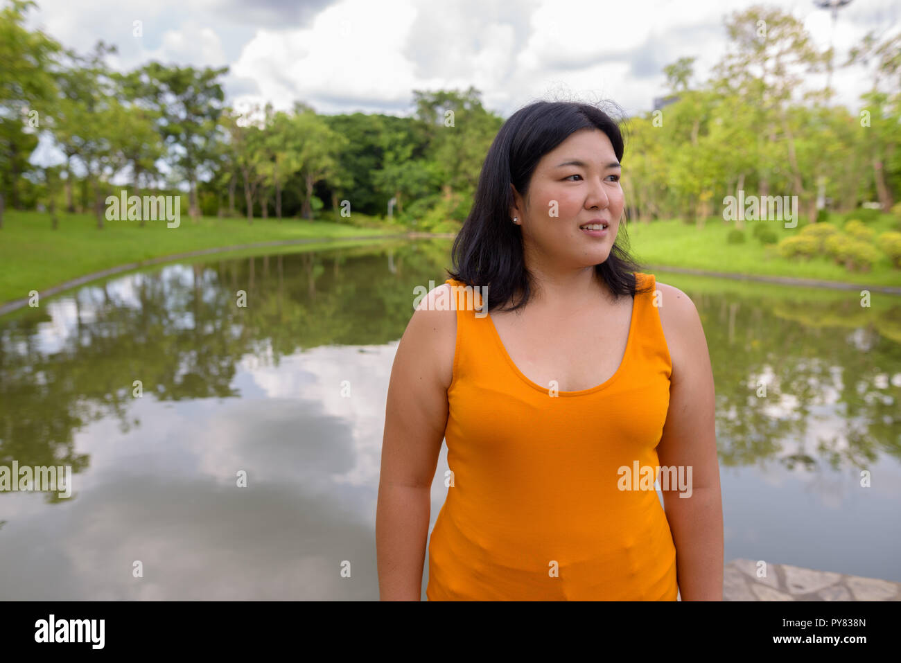 Beautiful overweight Asian woman thinking in park Stock Photo