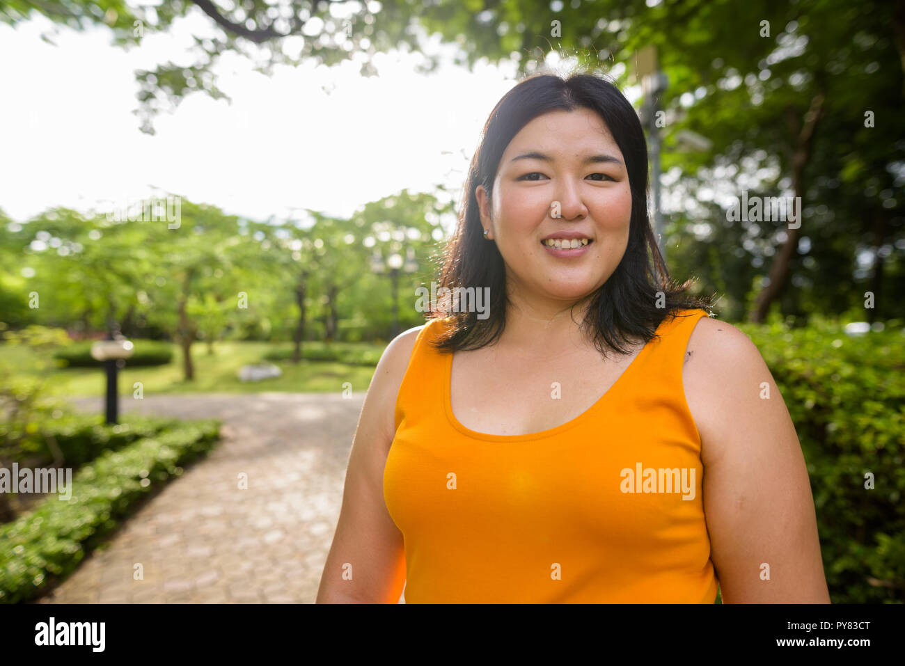 Beautiful overweight Asian woman smiling in park Stock Photo