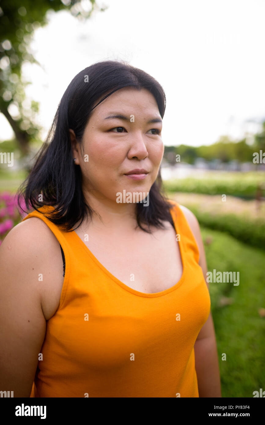 Beautiful overweight Asian woman thinking in park Stock Photo