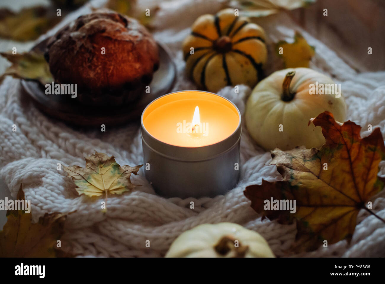 Burning candle in jar, autumn leaves and small decorative pumpkins ...