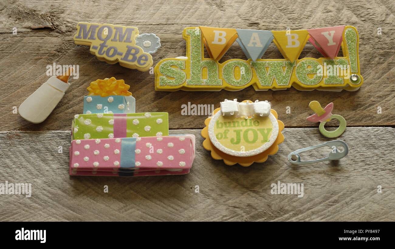 baby shower banner with mom to be bundle of joy written on cute buttons with a stack of presents on a natural wood background Stock Photo