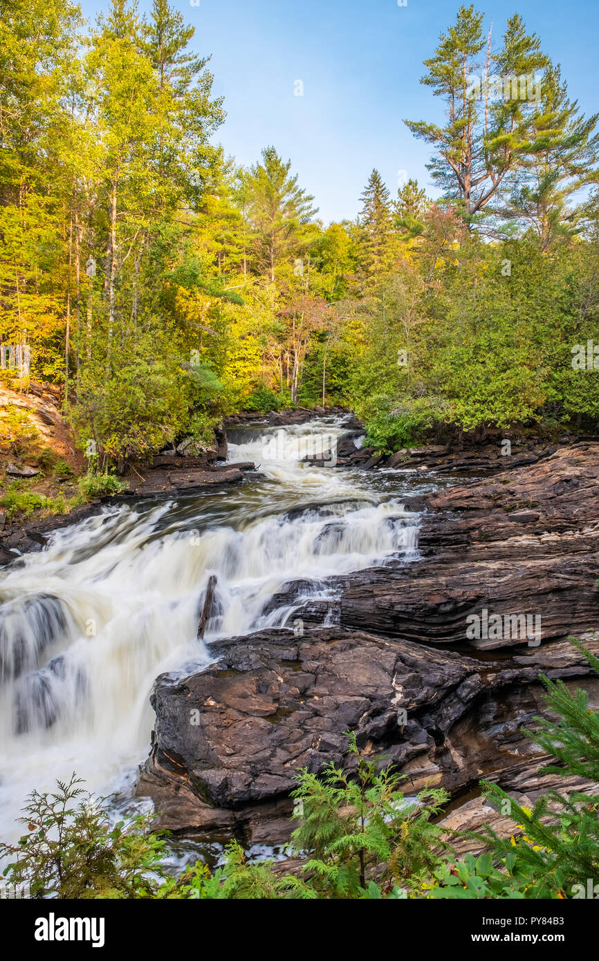 A view of the top of Egan Chute near Bancroft, Ontario as the water of the madawaska river curves and cascades down over the layers of rock between a  Stock Photo