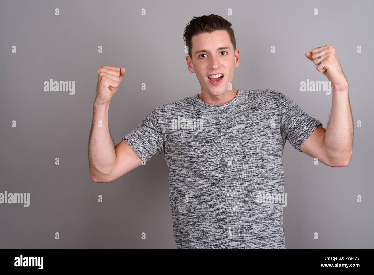 Young handsome man feeling excited with arms raised Stock Photo
