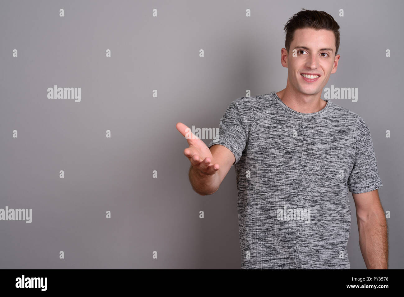 Young handsome man wearing gray shirt against gray background Stock Photo