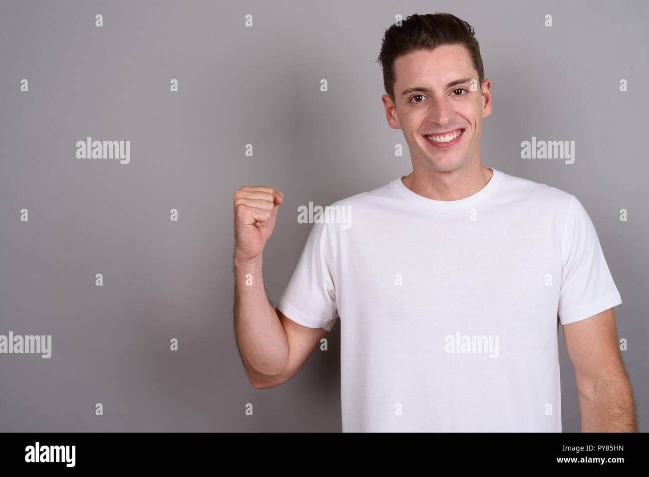 Young handsome man looking excited with arm raised Stock Photo