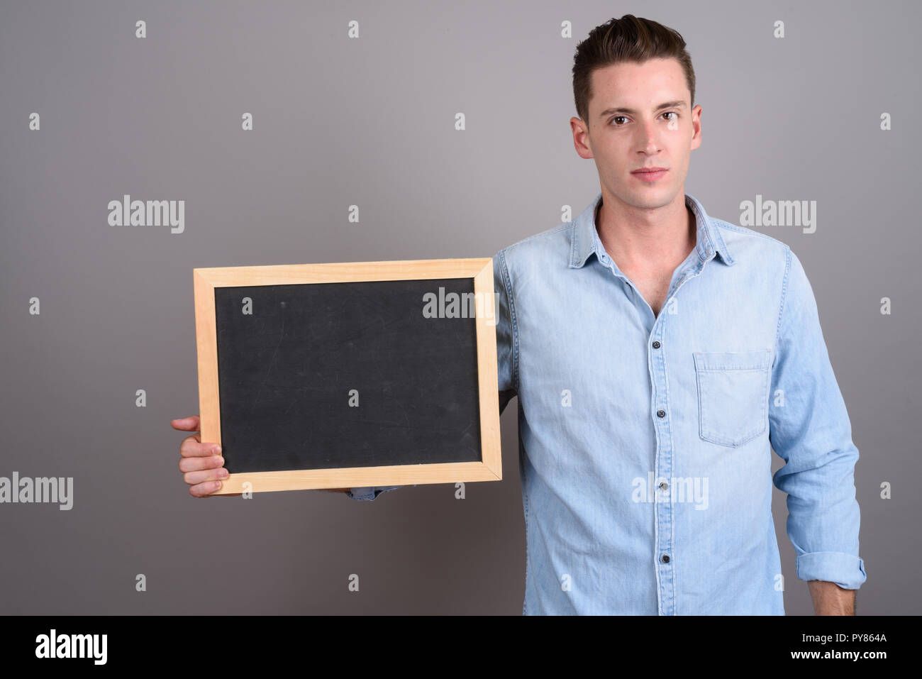 Young handsome man holding empty black board with copy space Stock Photo