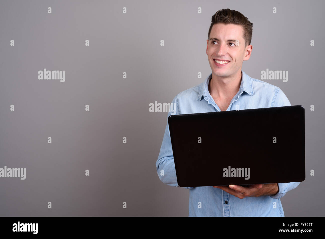 Young happy man using laptop computer while thinking Stock Photo