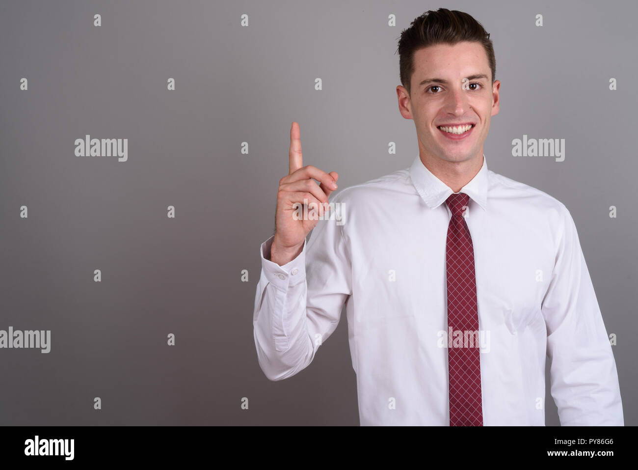 Portrait of young happy businessman pointing finger up Stock Photo