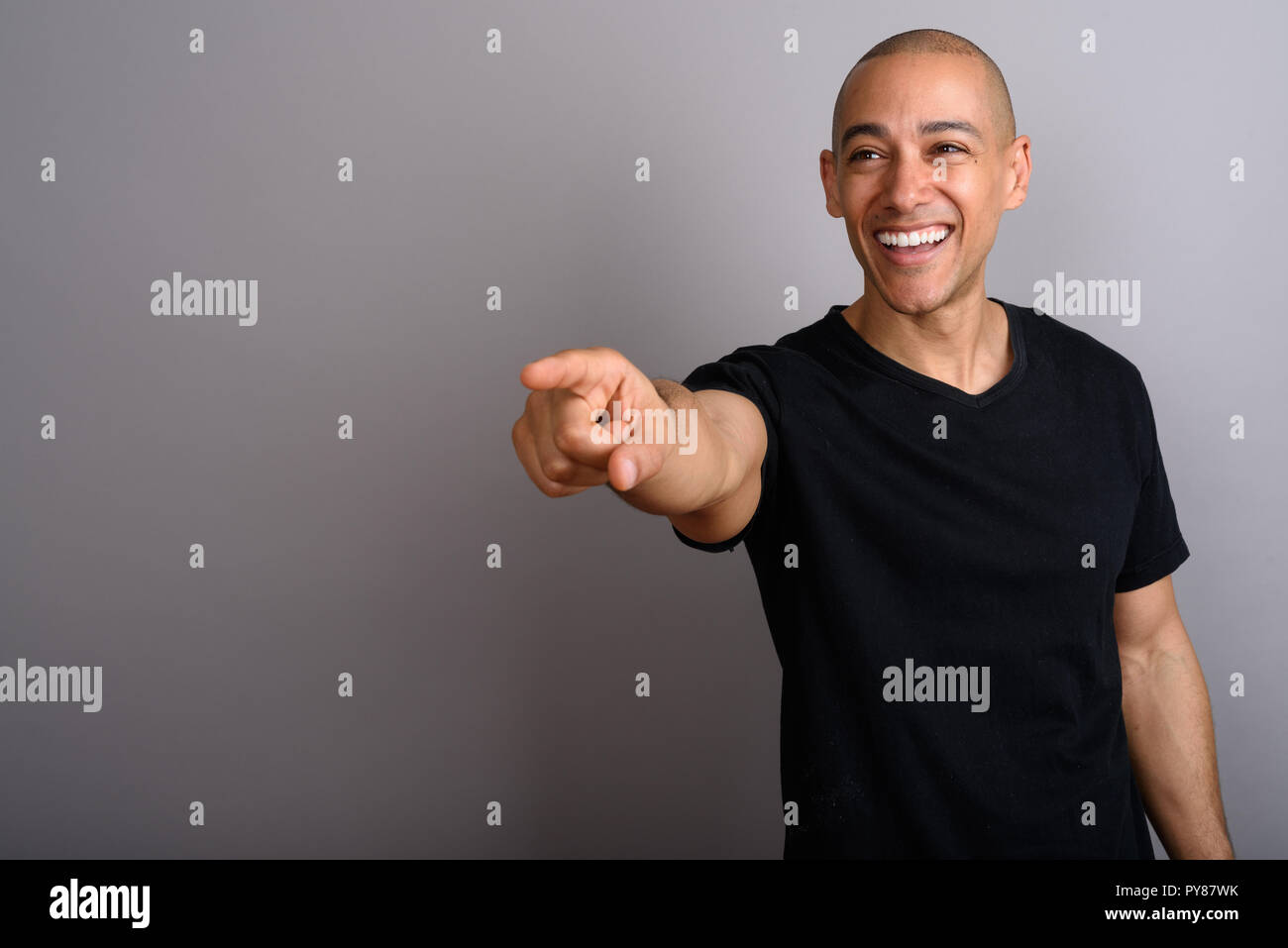 Handsome bald man smiling and pointing finger Stock Photo