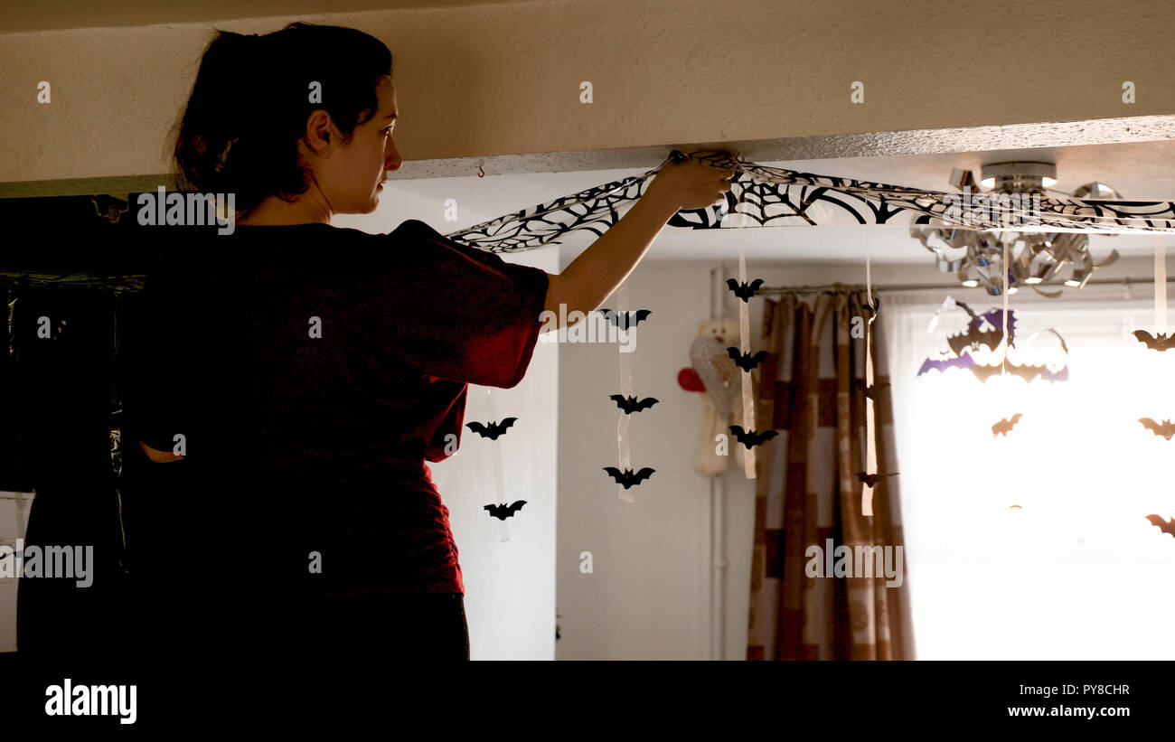 Young Woman Decorating Home For Halloween Celebration By