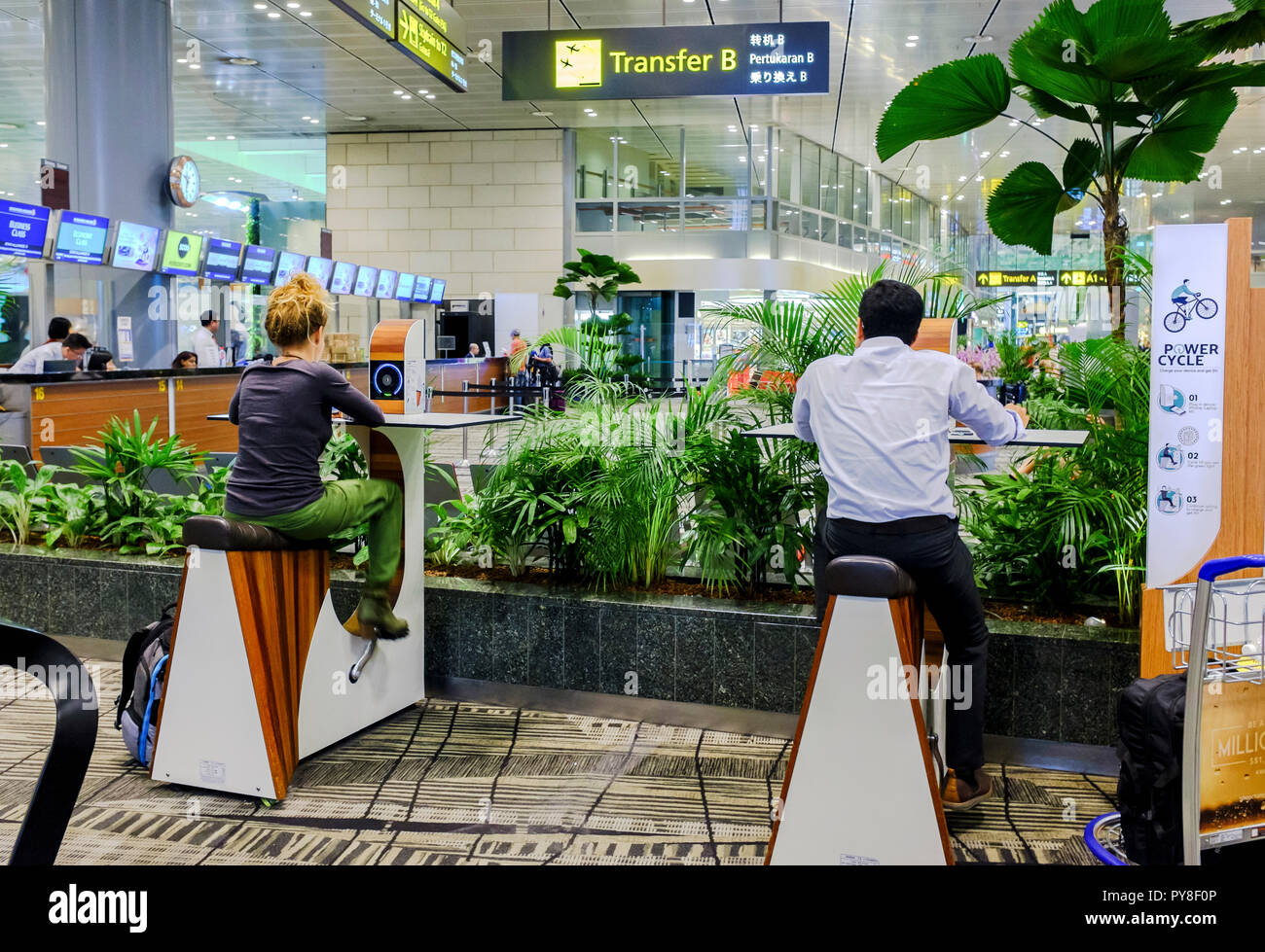 Backpacker and businessman pedalling at power cycle station to charge devices at Singapore airport, Sept 2018 Stock Photo