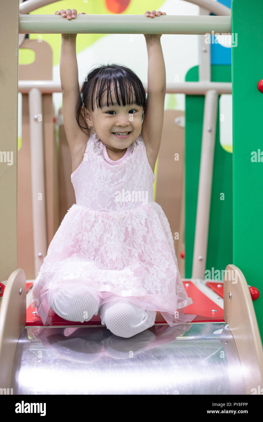 Asian Chinese little girl playing on the slide at indoor playground ...