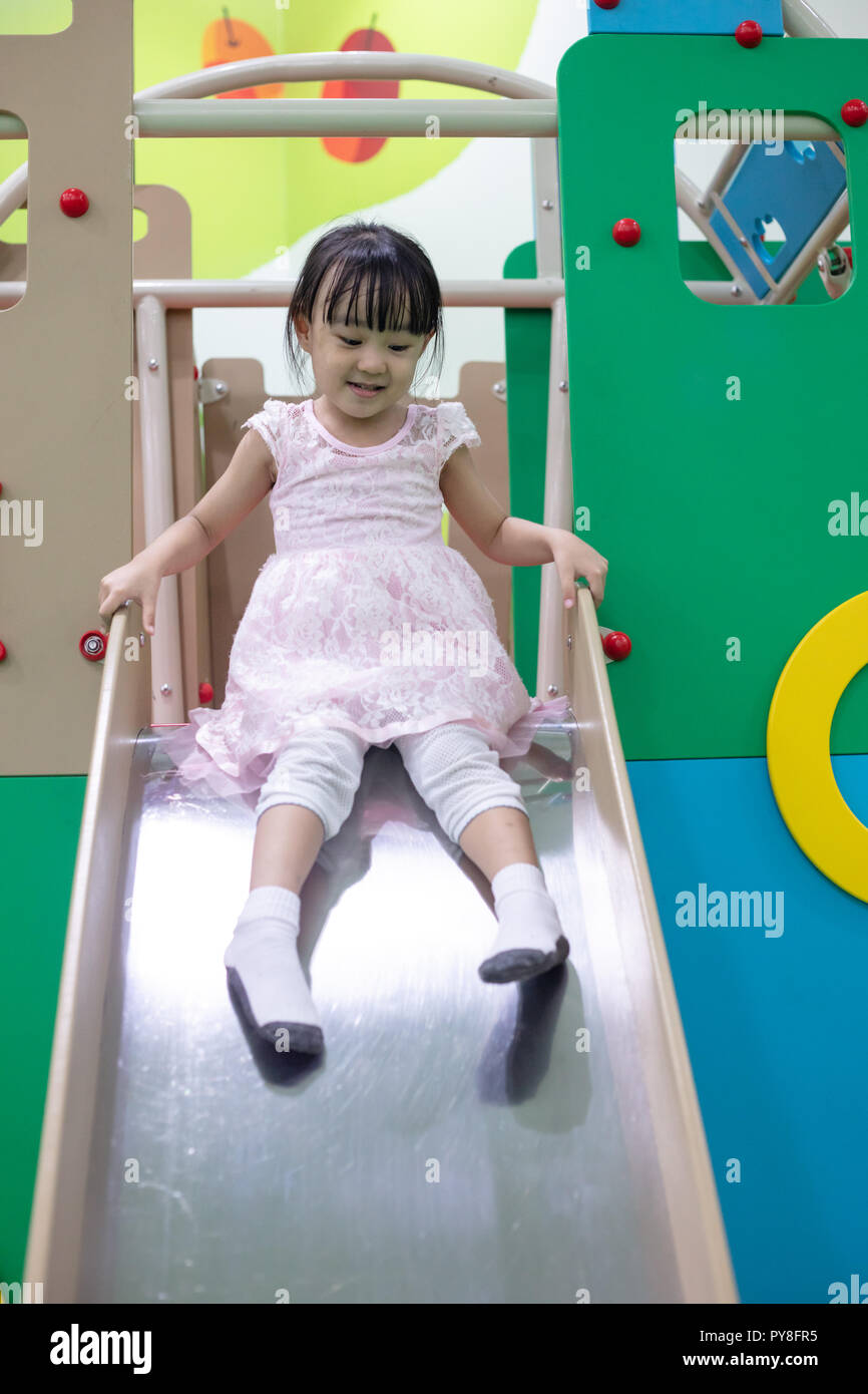 Asian Chinese little girl playing on the slide at indoor playground ...