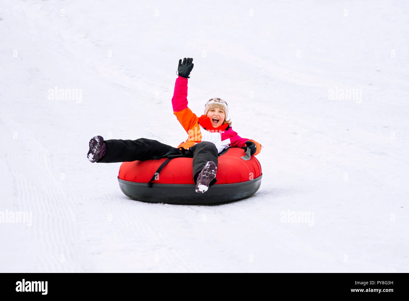 Child girl on snow tubes downhill at winter day. Stock Photo
