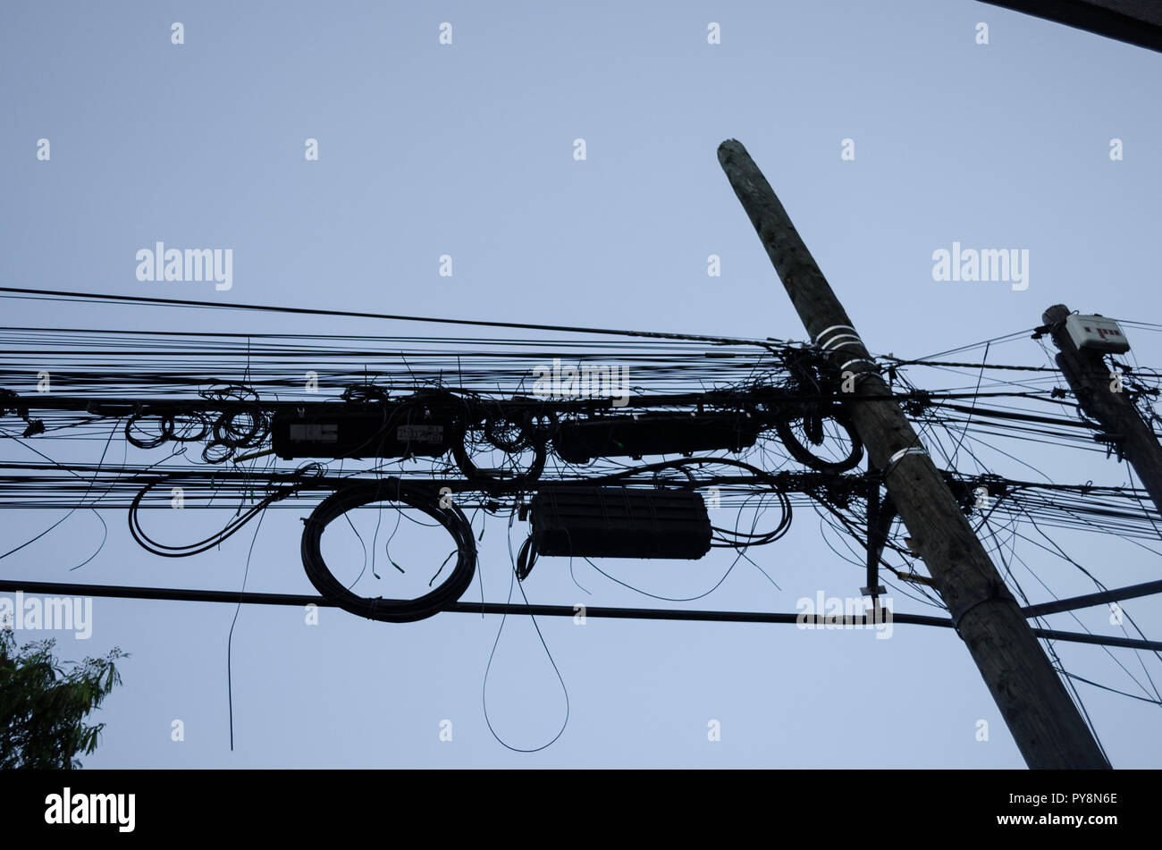 Light pole with many tangled cables, concept of disorder and problems in life, pattern of black cables on a wooden pole. Stock Photo