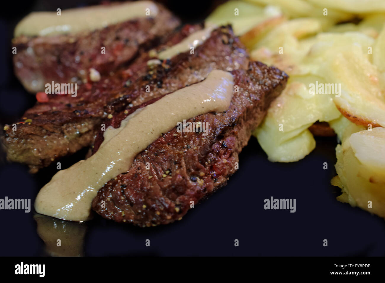 Spiced fillet beefsteak with creamy peppercorn sauce and gratin potatoes. Stock Photo