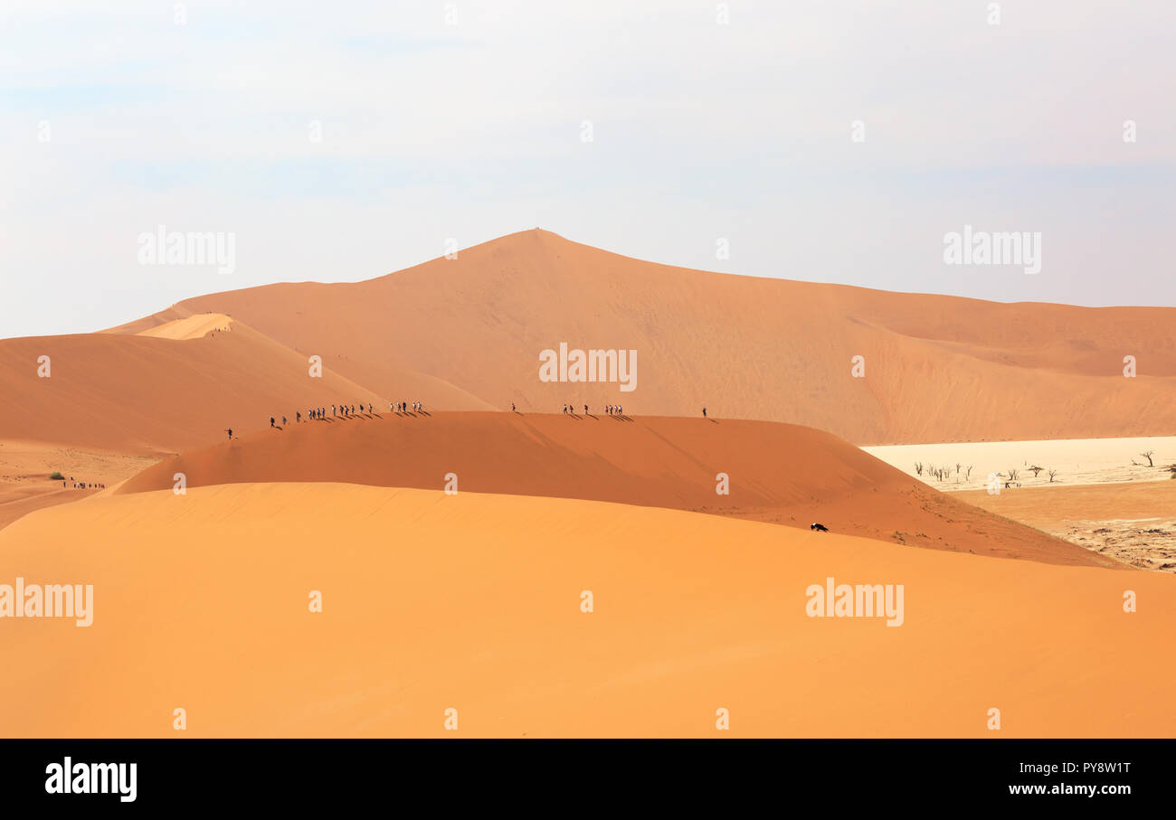 Namibia desert -  tourists walking the crest of sand dunes in the Namib desert at Sossusvlei, Namibia Africa Stock Photo