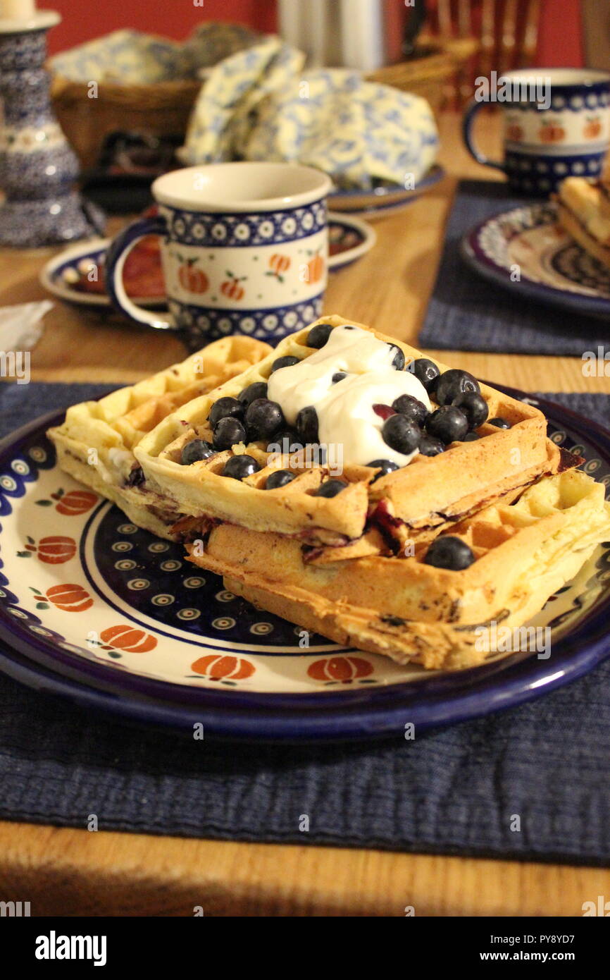 A plate of waffles, blueberries and cream on a breakfast table Stock Photo