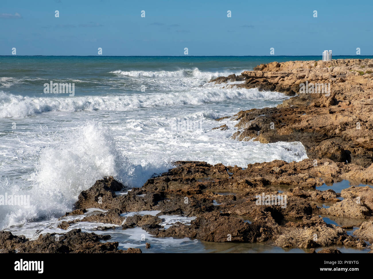 People watch as large waves crash into the shore near Paphos Castle, Paphos, Cyprus Stock Photo