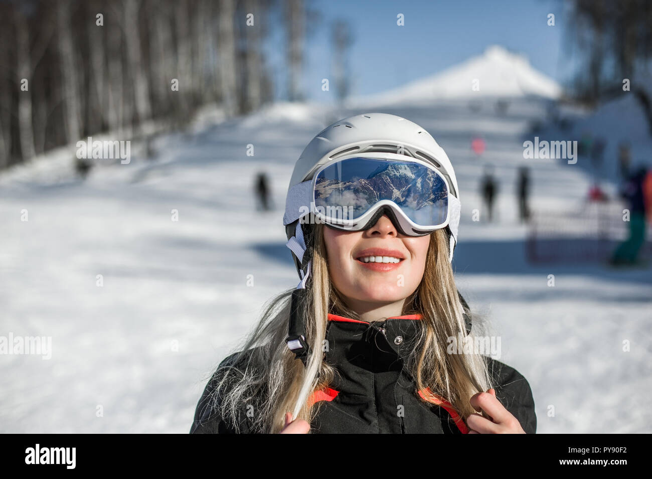 Macro portrait. Young adult woman snowboarder or skier in snow winter on the mountainside the ski mask or goggles reflect the mountains Stock Photo