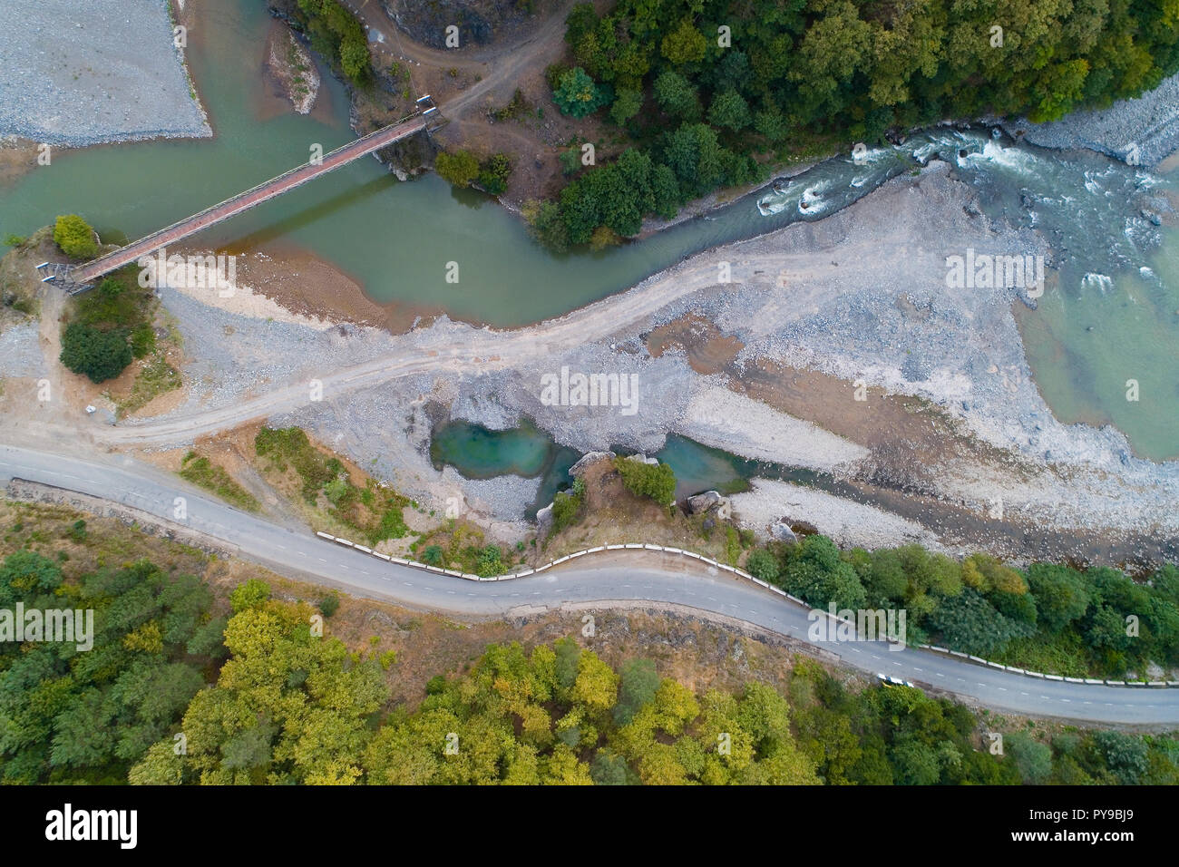 A winding mountain road passes by the river. Aerial photography. Stock Photo